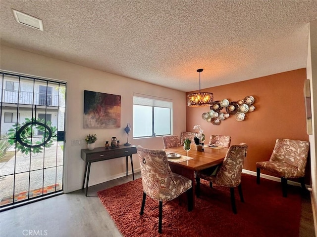 dining room featuring hardwood / wood-style floors, a chandelier, and a textured ceiling