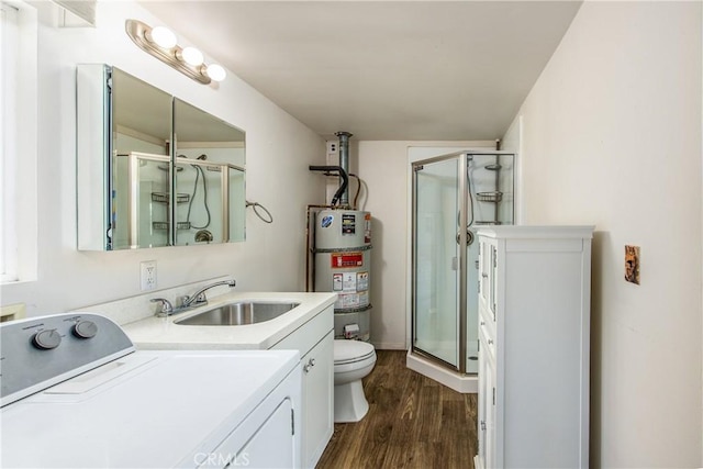 bathroom with hardwood / wood-style flooring, an enclosed shower, washer / clothes dryer, vanity, and strapped water heater