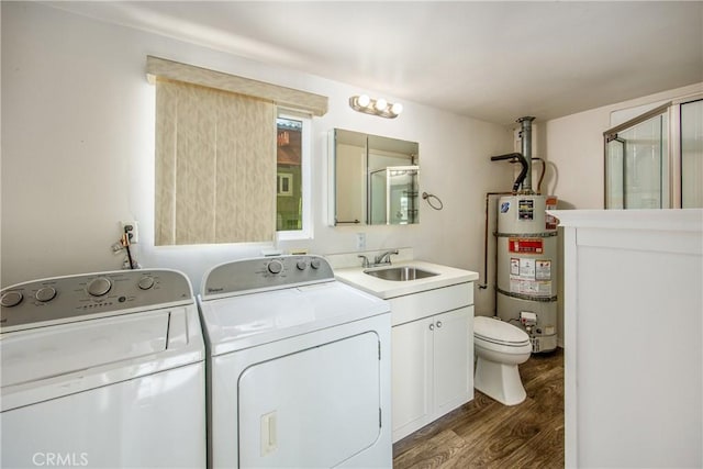 clothes washing area with dark hardwood / wood-style flooring, sink, separate washer and dryer, and strapped water heater