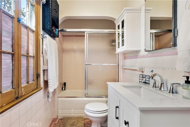 full bathroom with toilet, tile walls, combined bath / shower with glass door, backsplash, and vanity