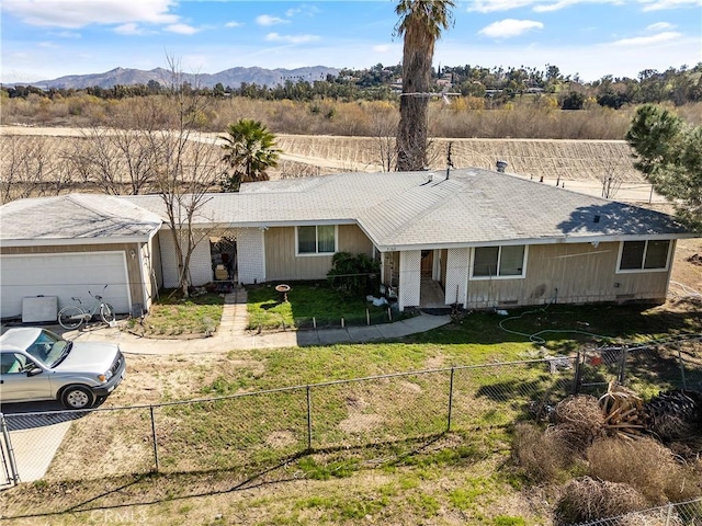 ranch-style home with a garage, a mountain view, and a front lawn