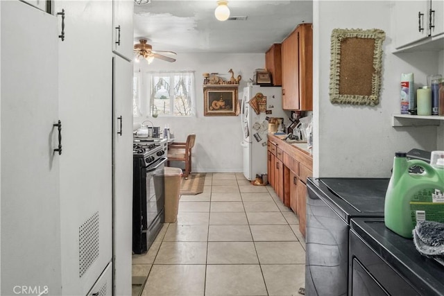 kitchen with white fridge, black range with gas cooktop, ceiling fan, and light tile patterned floors