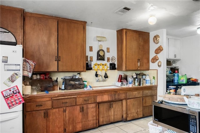 kitchen with backsplash, white fridge, and light tile patterned floors