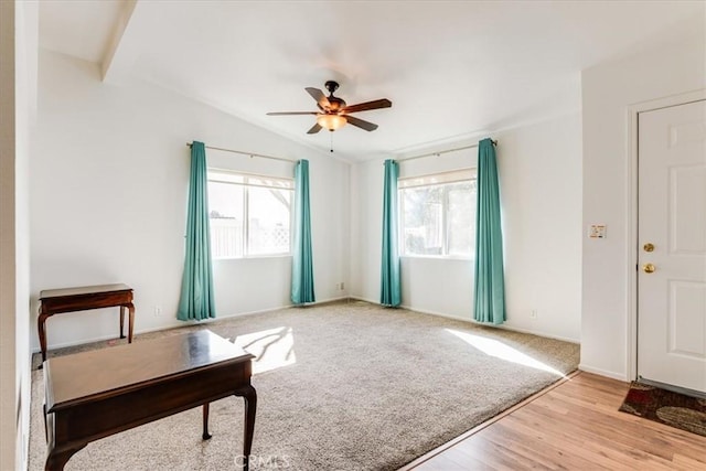 living area with light carpet, baseboards, a ceiling fan, lofted ceiling, and light wood-style floors