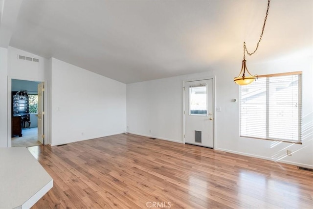 unfurnished living room with lofted ceiling, light wood-style flooring, and visible vents