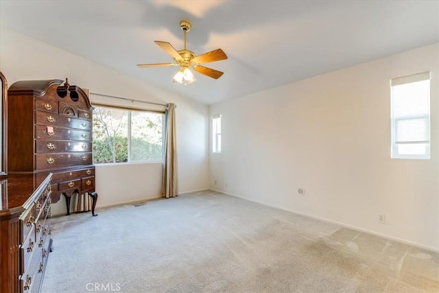 empty room featuring light carpet, visible vents, lofted ceiling, and a ceiling fan