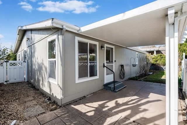 view of home's exterior with entry steps, fence, an attached carport, and a patio