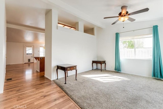 empty room featuring vaulted ceiling with beams, light wood finished floors, visible vents, and a ceiling fan