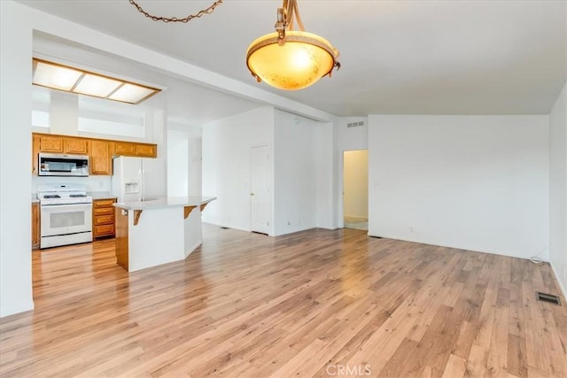 kitchen featuring open floor plan, light countertops, white appliances, and brown cabinets