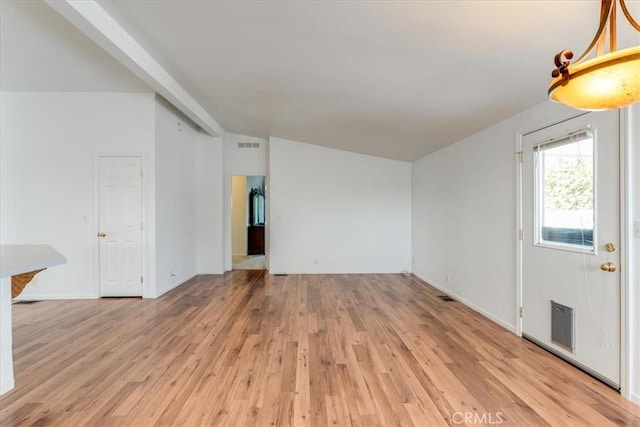 unfurnished living room with light wood-style floors, visible vents, and vaulted ceiling