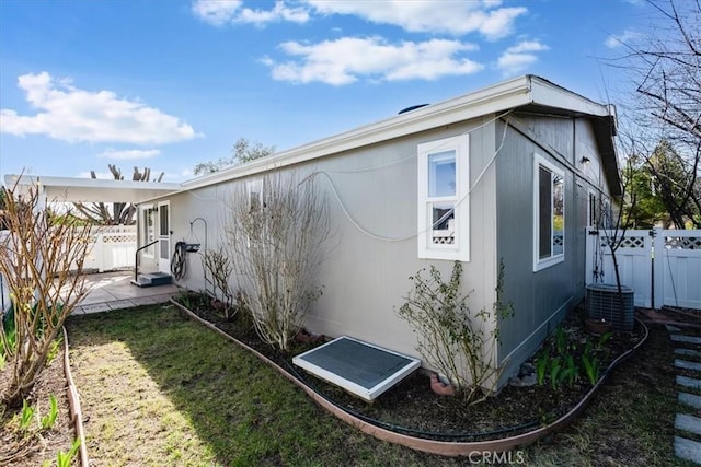 view of side of home featuring fence and a lawn