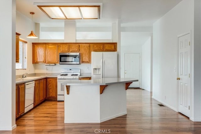 kitchen featuring light countertops, white appliances, brown cabinetry, and hanging light fixtures