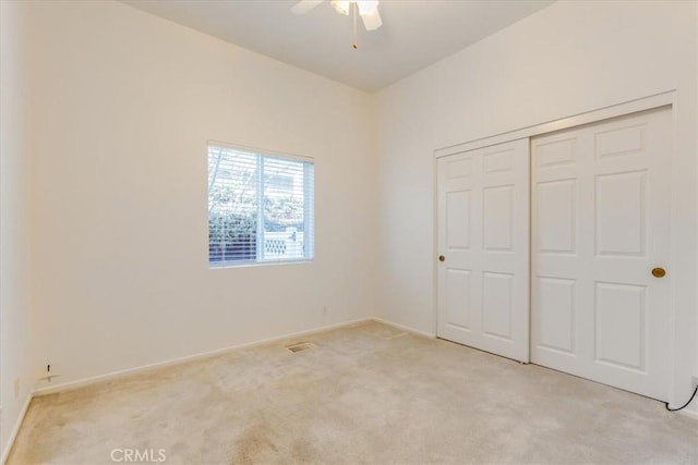 unfurnished bedroom with a closet, visible vents, a ceiling fan, light carpet, and baseboards