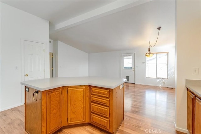 kitchen with brown cabinets, a center island, pendant lighting, and light countertops