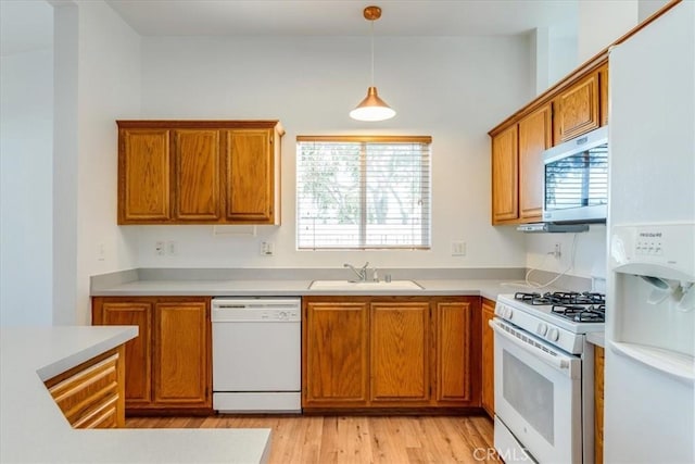 kitchen with white appliances, pendant lighting, light countertops, and a sink