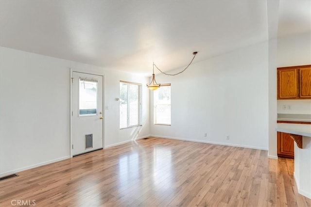 unfurnished dining area featuring light wood-style floors, visible vents, and baseboards