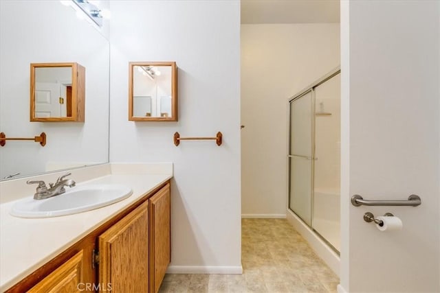 full bath with a stall shower, vanity, and baseboards