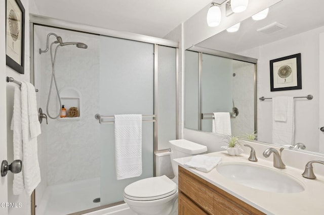 bathroom featuring vanity, a shower with door, and toilet