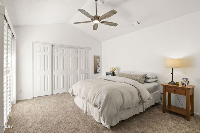 carpeted bedroom featuring ceiling fan, vaulted ceiling, multiple windows, and a closet