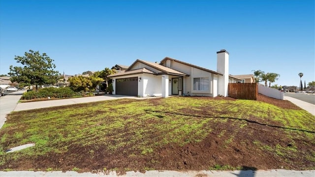 view of front of house featuring a garage, concrete driveway, a front lawn, and fence