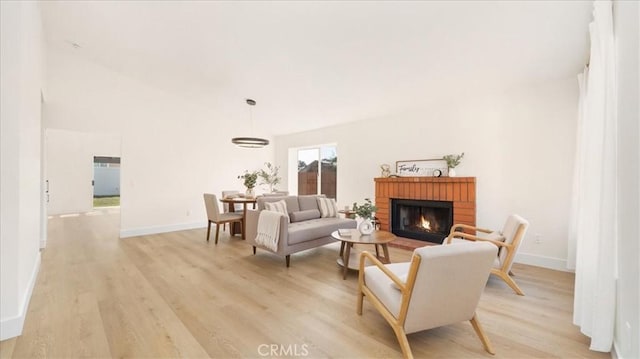 sitting room featuring baseboards, light wood-type flooring, and a brick fireplace