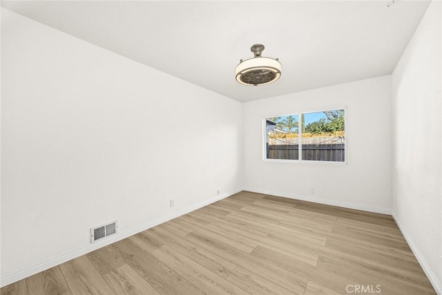 unfurnished room with light wood-type flooring, visible vents, and baseboards