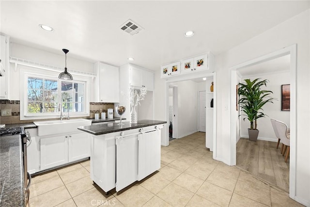 kitchen featuring decorative light fixtures, visible vents, decorative backsplash, white cabinets, and a sink