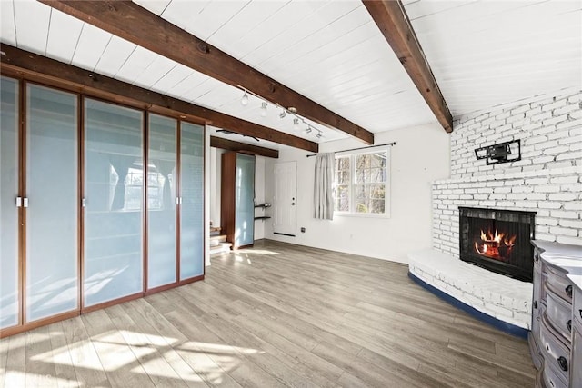 unfurnished living room featuring a fireplace, beamed ceiling, and wood finished floors