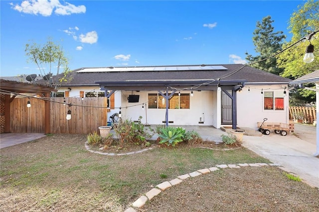 view of front of property featuring fence, solar panels, and stucco siding