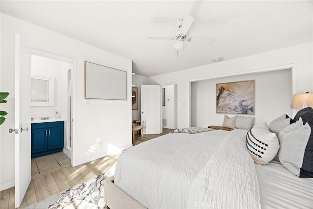 bedroom featuring connected bathroom, a sink, visible vents, baseboards, and light wood-style floors