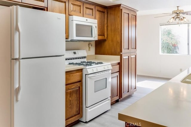 kitchen with ceiling fan, white appliances, and light hardwood / wood-style flooring