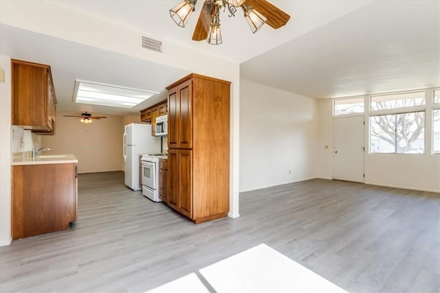 kitchen with white appliances, light wood-type flooring, ceiling fan, and sink