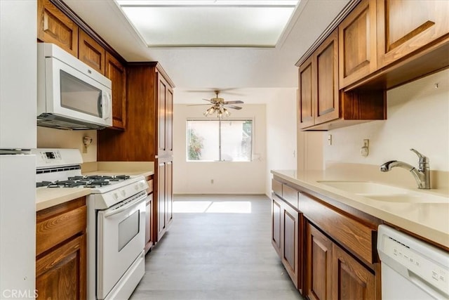 kitchen with ceiling fan, sink, white appliances, and light wood-type flooring