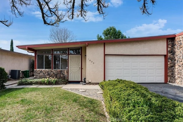 ranch-style home with a garage, cooling unit, and a front lawn