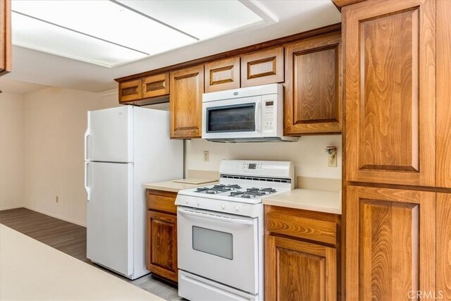 kitchen with white appliances and light hardwood / wood-style flooring