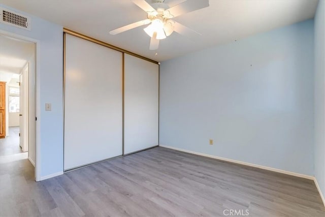 unfurnished bedroom featuring ceiling fan, light hardwood / wood-style floors, and a closet