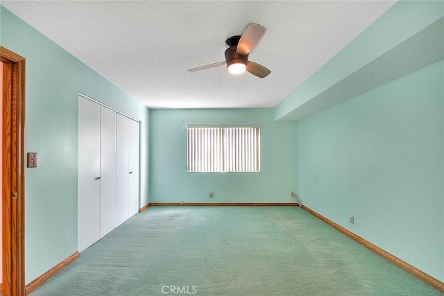 unfurnished bedroom featuring a textured ceiling, a closet, light carpet, and ceiling fan