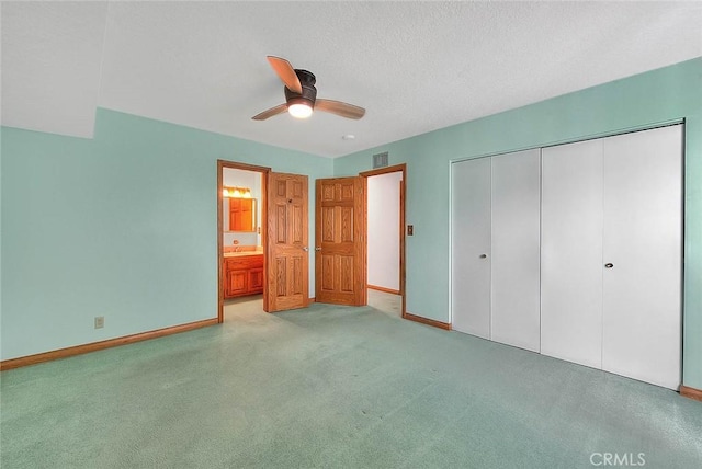 unfurnished bedroom featuring a textured ceiling, a closet, light colored carpet, and ceiling fan