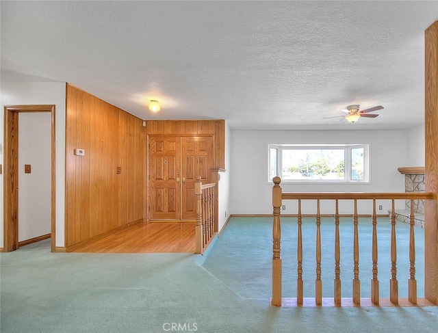 hallway with wooden walls, carpet floors, and a textured ceiling