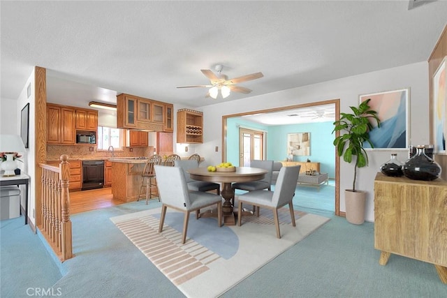 dining space featuring sink, light colored carpet, and ceiling fan