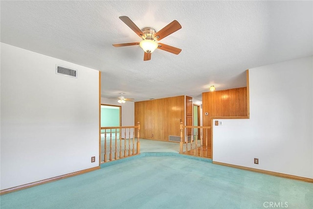 carpeted empty room with wood walls and a textured ceiling