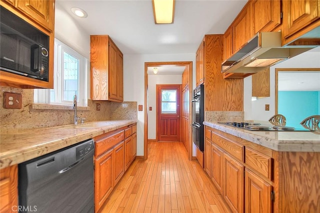 kitchen with exhaust hood, backsplash, black appliances, and a wealth of natural light