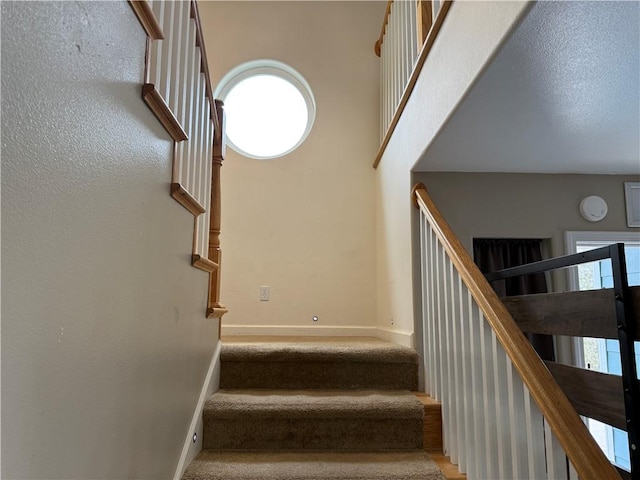 stairway featuring a towering ceiling and baseboards