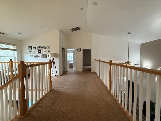 hall with lofted ceiling, light carpet, visible vents, and an upstairs landing