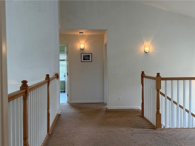 hallway with carpet, baseboards, and an upstairs landing