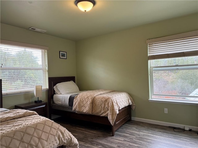 bedroom featuring dark wood finished floors, visible vents, and baseboards