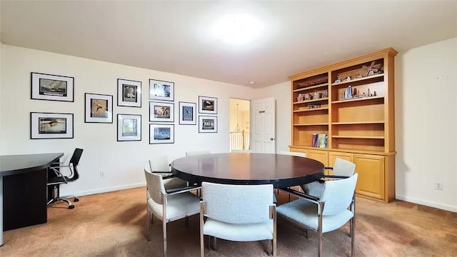 dining space featuring light carpet and baseboards