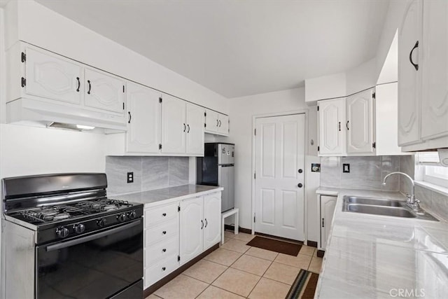 kitchen with sink, white cabinetry, custom range hood, black range with gas stovetop, and stainless steel fridge