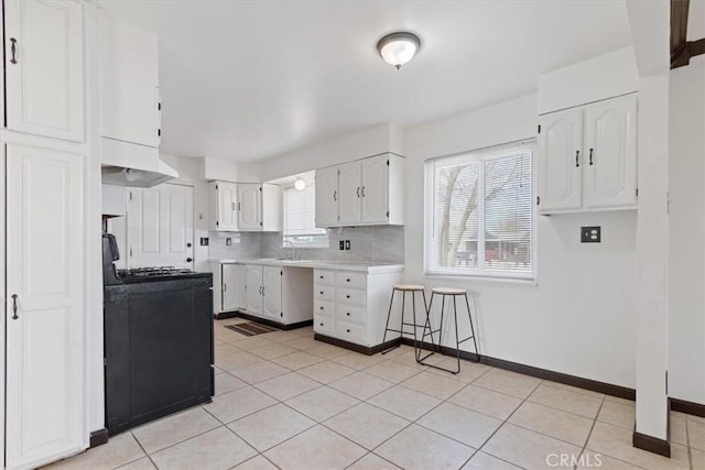 kitchen featuring tasteful backsplash, premium range hood, sink, white cabinetry, and range with gas cooktop