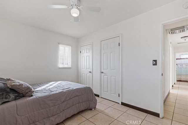 tiled bedroom featuring multiple windows, multiple closets, and ceiling fan